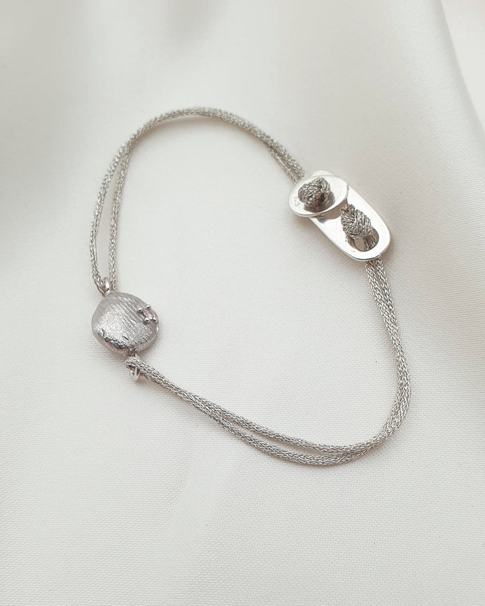 Silver bracelet with a clasp on a light gray background