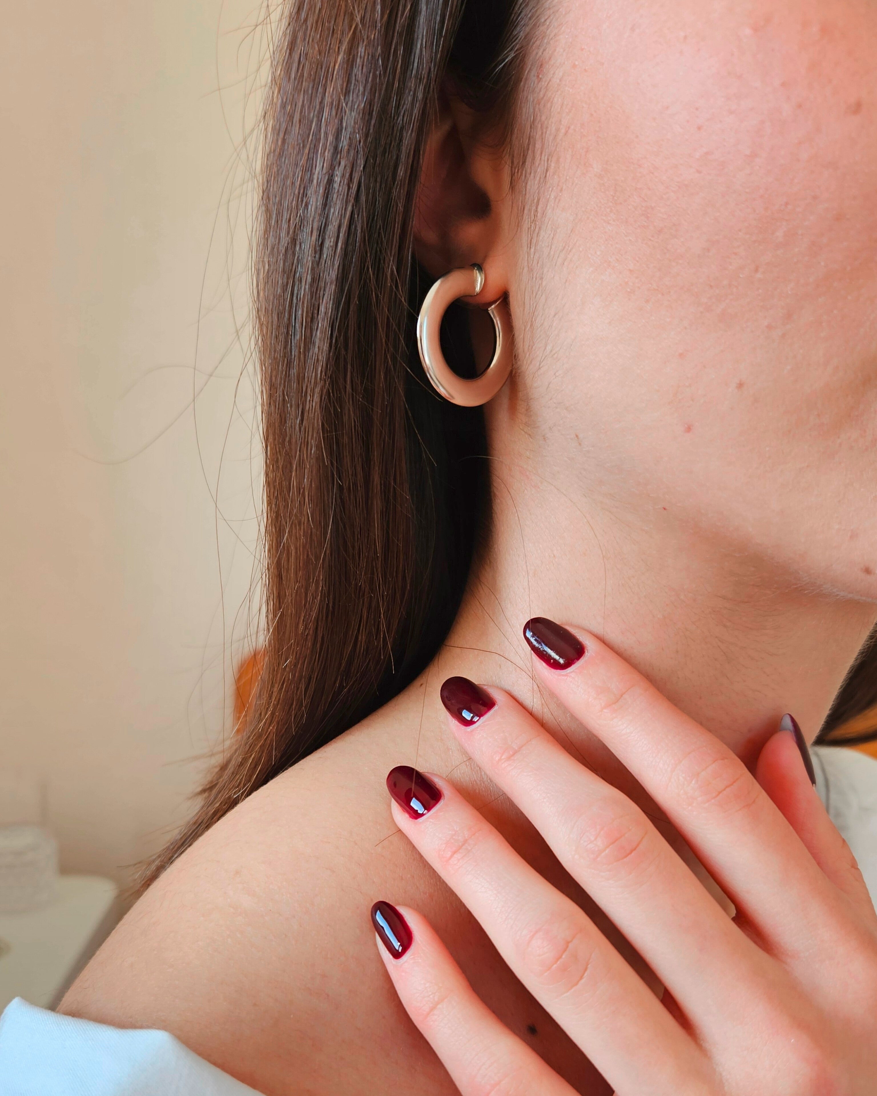 Close-up of a person wearing hoop earrings with a neutral background